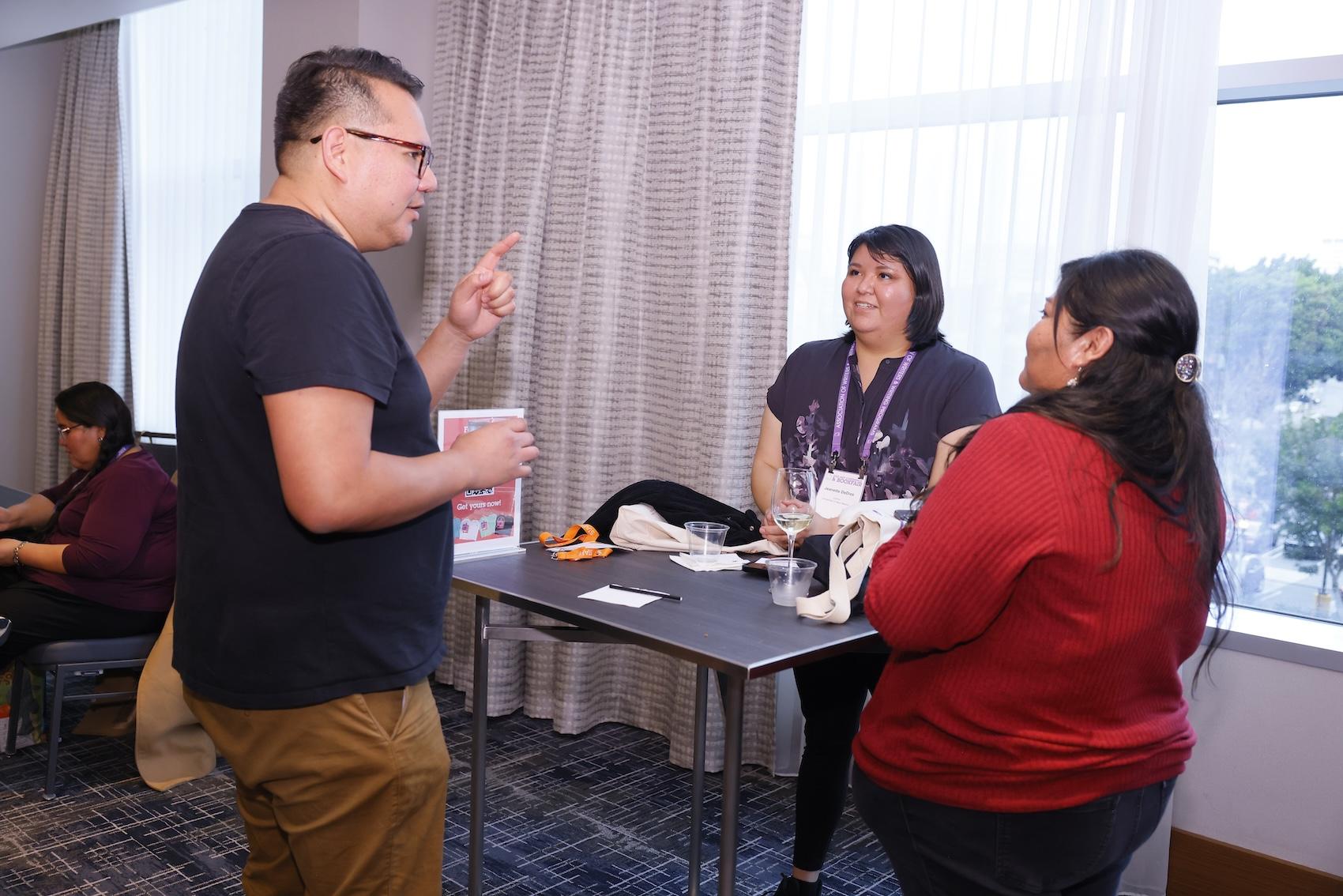 Jake Skeets standing and chatting with two people at a reception table