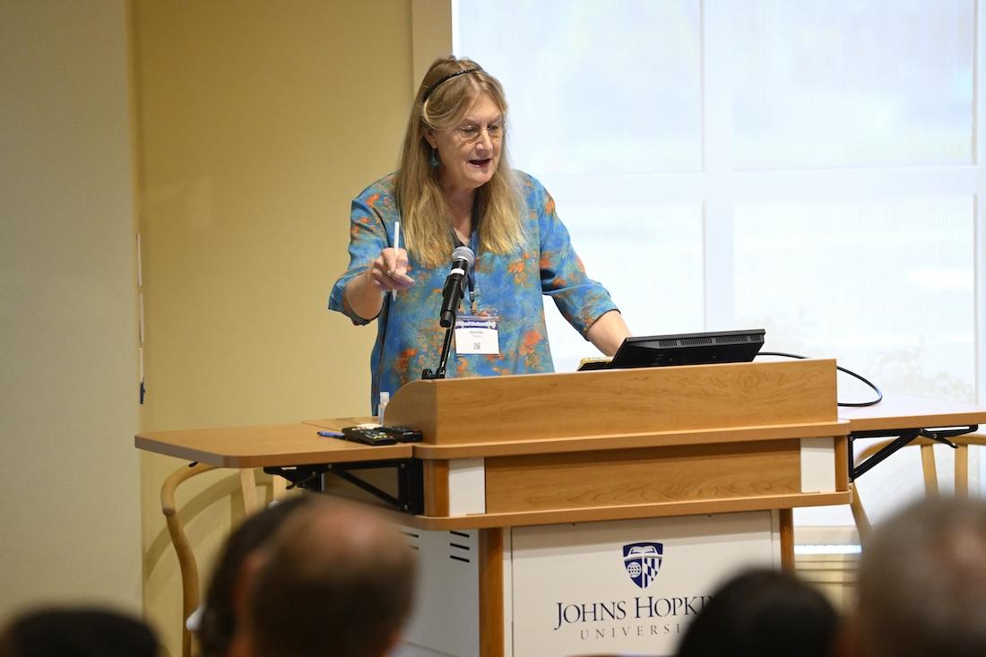 A woman speaking from a podium with Johns Hopkins University branding