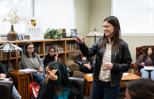 Writing instructor speaking with a class in a library